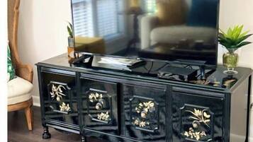 Een zwarte entertainmentkast met een flatscreen televisie, decoratieve kastdeurtjes en een kamerbreed tapijt met een patroon.