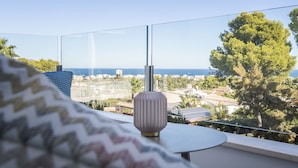 Un balcón con vistas despejadas al mar y al paisaje urbano, una lámpara moderna y un tejido estampado.