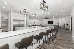 A modern kitchen with a central island, bar stools, and a ceiling fan.