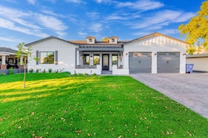 A two-story house with a front porch, a garage, and a well-maintained lawn.