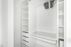 A white walk-in closet with multiple shelves and hanging space.