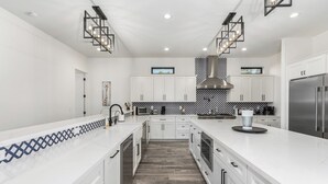 Una cocina moderna con armarios blancos, una isla central y un salpicadero con diseño.