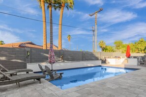 A swimming pool with lounge chairs and a small bar area.