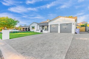 Une maison moderne à deux étages, dotée d’une allée pavée, d’un garage et d’une pelouse bien entretenue.