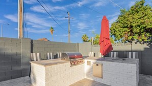 An outdoor barbecue area with a grill, seating, and a red umbrella. - Arcadia/Scottsdale 4bedroom/4.5bath Camelback Mountain New Build-Prime Location (Phoenix)