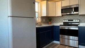 A kitchen with white cabinets, a stainless steel refrigerator, a microwave, and an oven. - Delightful Sleek Modern 2 Bed 1 Bath apt (Anchorage)