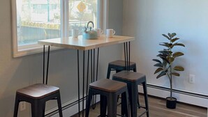 A small kitchen with a window, a table with a kettle, and three stools. - Delightful Sleek Modern 2 Bed 1 Bath apt (Anchorage)