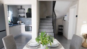 A modern kitchen with a built-in oven, a dining area with a white table set for two, and a staircase leading to another level. - Villa Lota with a heated pool, sauna & E-car charger (Sveti Ivan Dobrinjski (Krk))