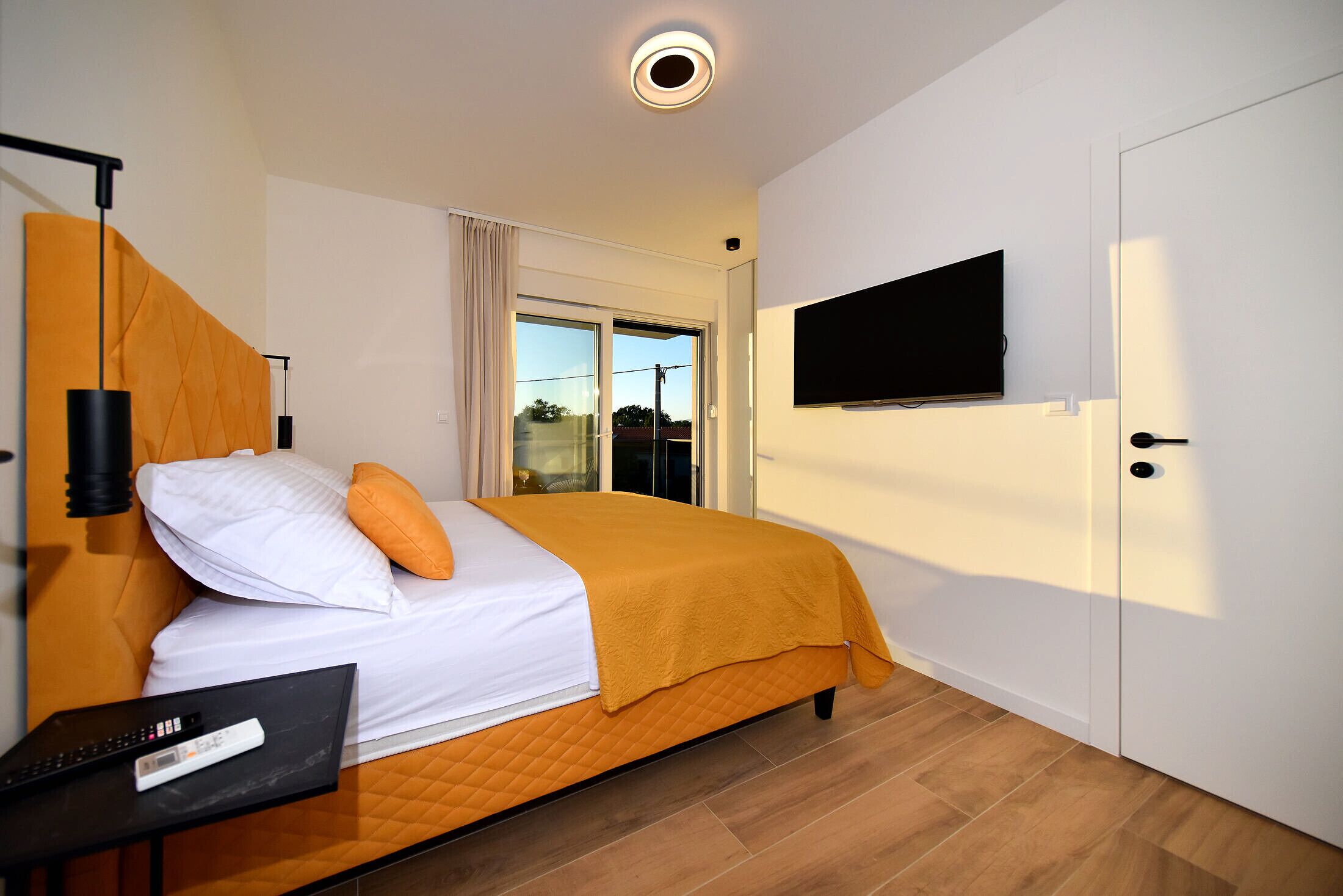 A hotel room with a bed, a TV mounted on the wall, and a door.