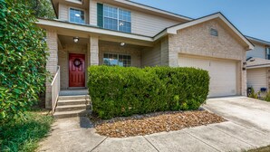 A two-story house with a red door, a front porch, and a well-maintained lawn. - #Rental Welcomes #Nurses #Sea World #JBSA #Medical Center #USAF #ARMY #BMT #NSCA (San Antonio)