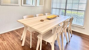 A dining area with a wooden table and chairs, a bowl of fruit, and a window with blinds. - #Rental Welcomes #Nurses #Sea World #JBSA #Medical Center #USAF #ARMY #BMT #NSCA (San Antonio)