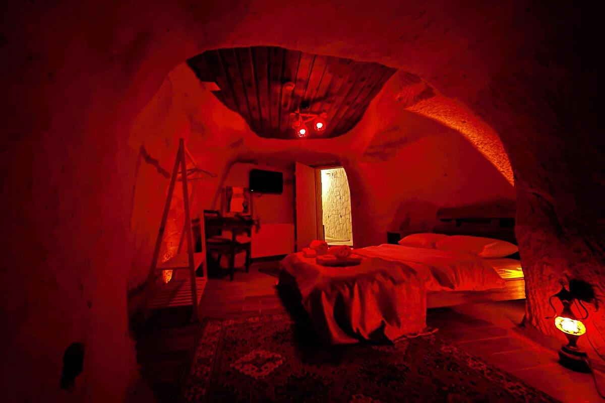 A cozy, dimly lit room with a bed, a small table, and a lamp.