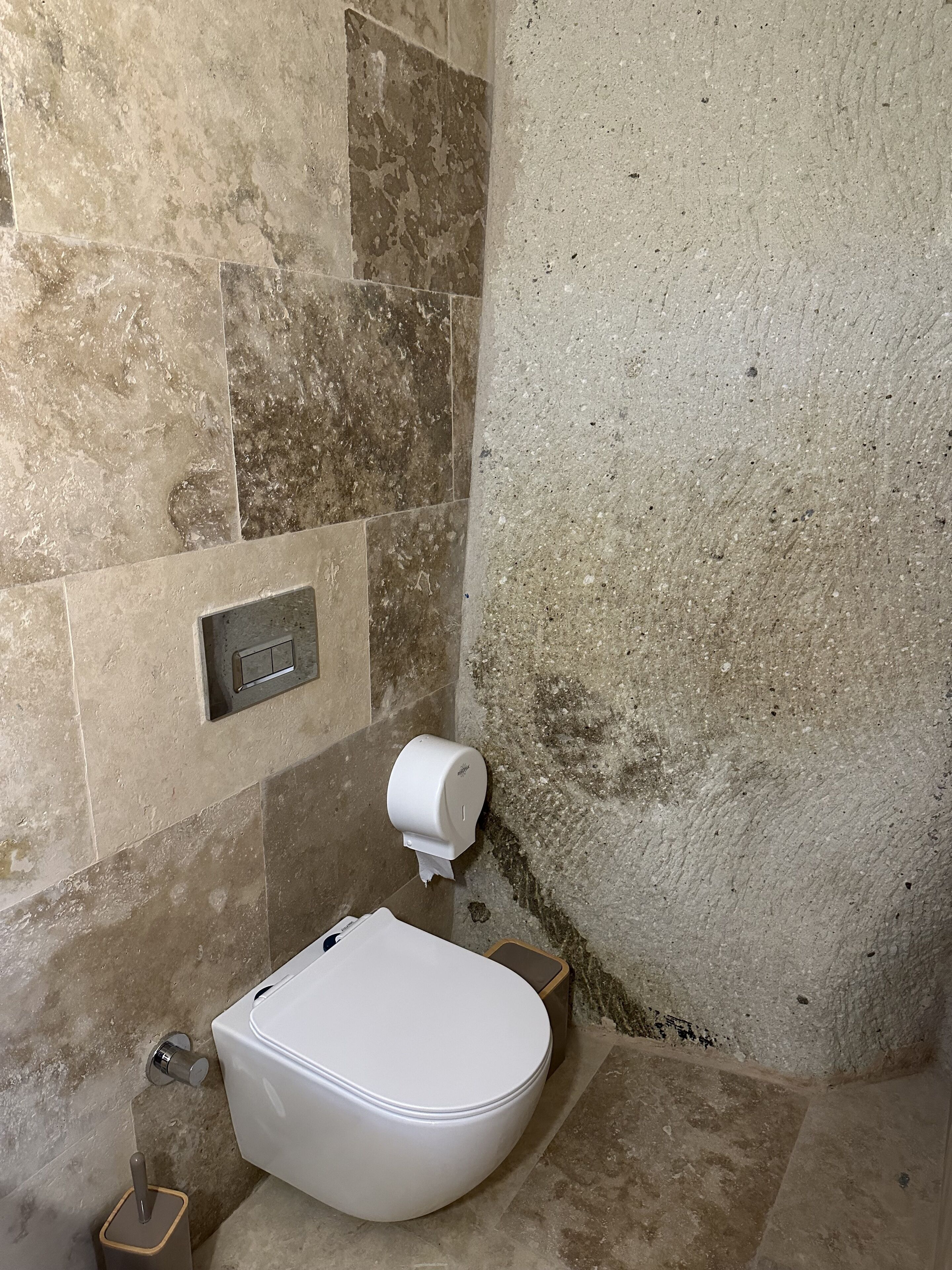 A bathroom with a white toilet, a paper towel dispenser, and a hand dryer.