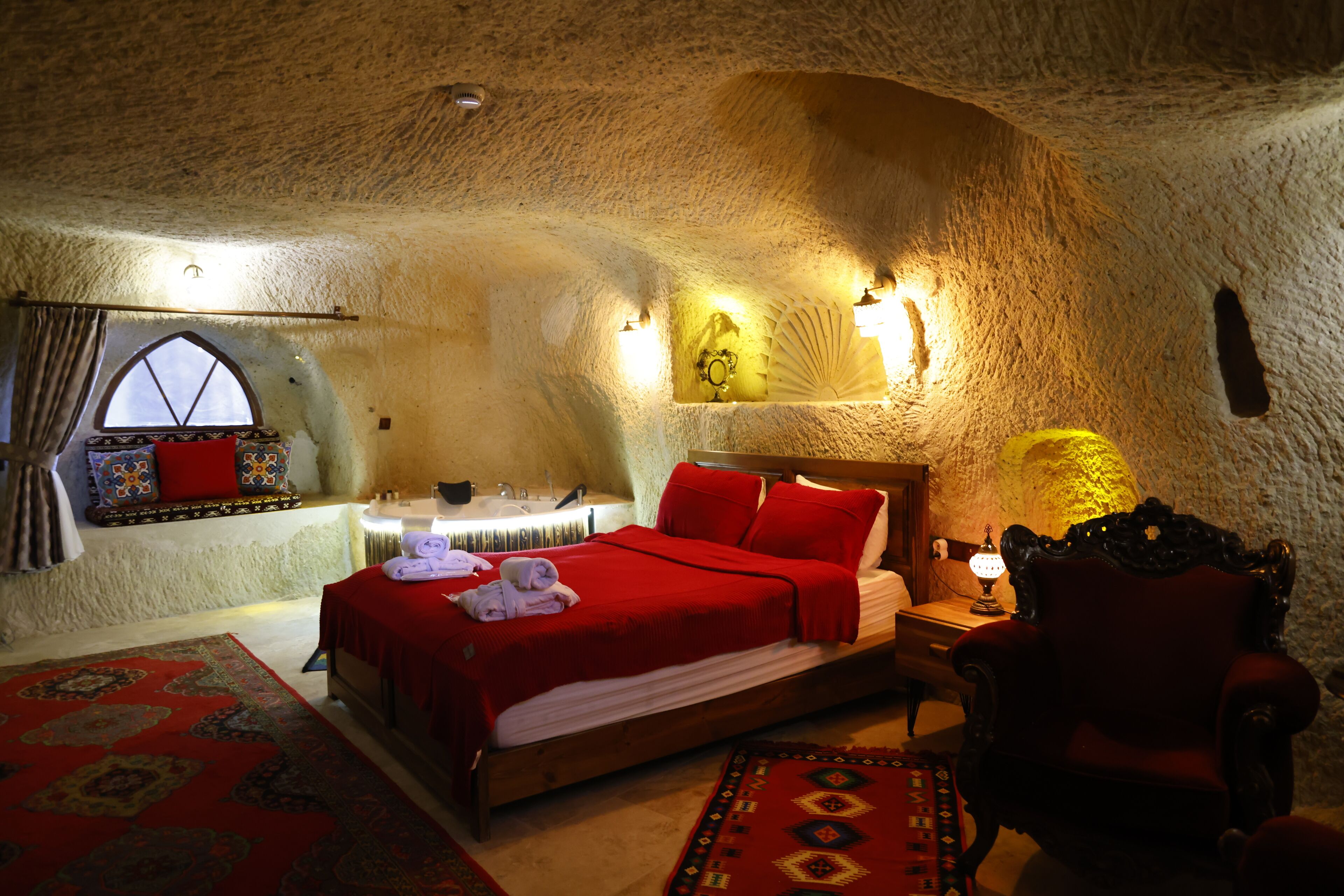 A room with a bed, a chair, a table, and a window.