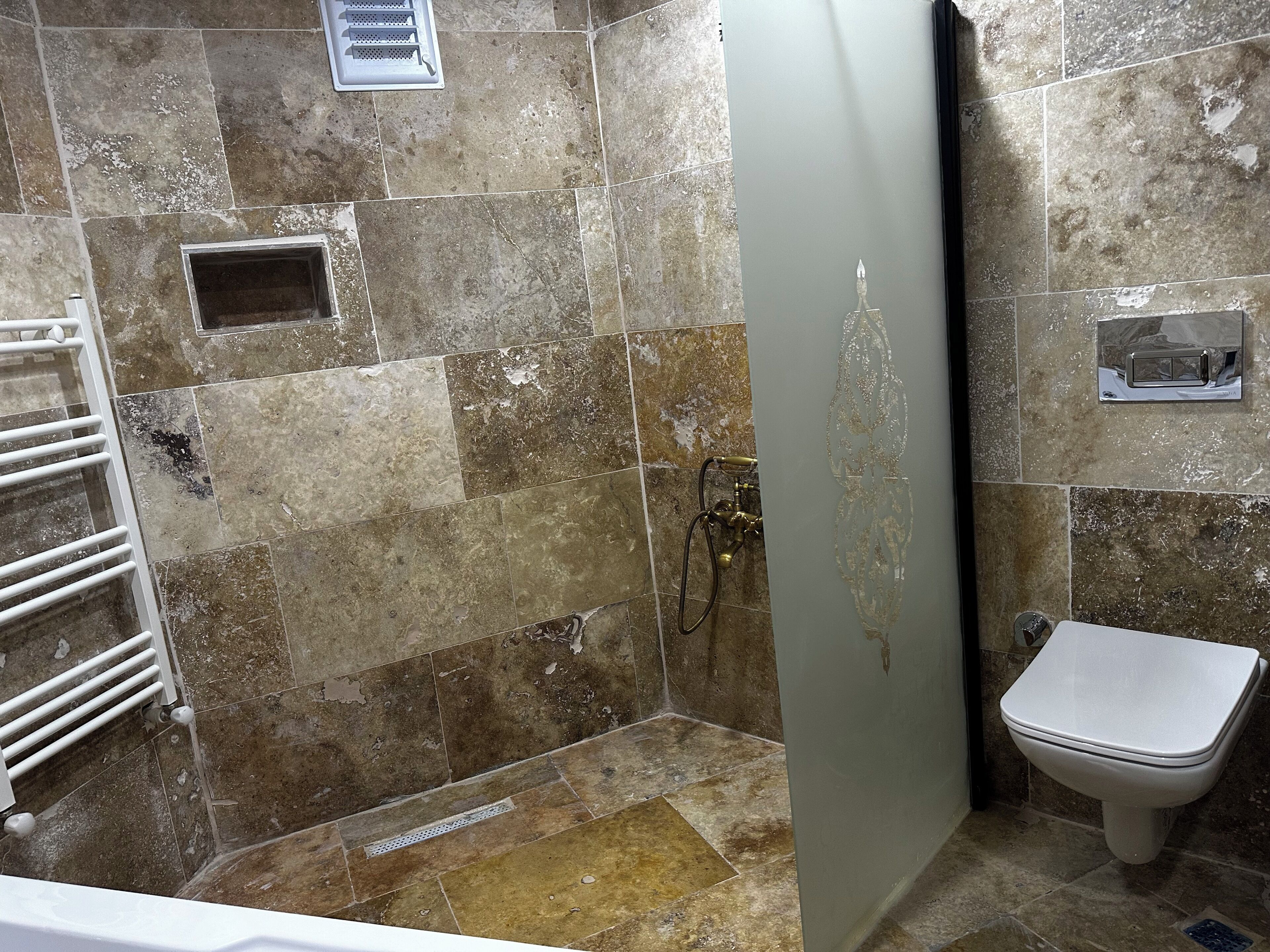 A bathroom with a shower, toilet, and a towel rack.