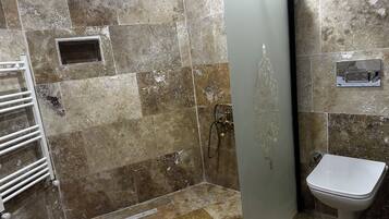 A bathroom with a shower, toilet, and a towel rack.