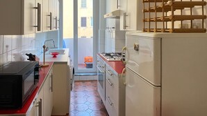 Eine kleine Küche mit weißen Schränken, einer roten Arbeitsplatte, einem eingebauten Herd und einem Kühlschrank.
