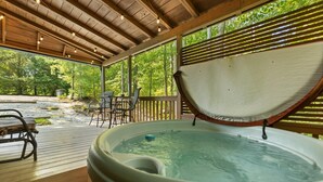 Un bain à remous sous une pergola en bois, avec vue sur une zone boisée.