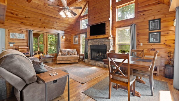 Un intérieur chaleureux de chalet en bois, avec une cheminée, des meubles en bois et de grandes fenêtres.