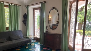 Quarto com sofá, mesa pequena, cômoda e espelho.