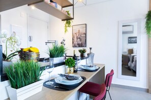Moderni keittiö, jossa on puinen työtaso, sisäänrakennettu yrttitarha ja ruokailutila, jossa on punainen tuoli.