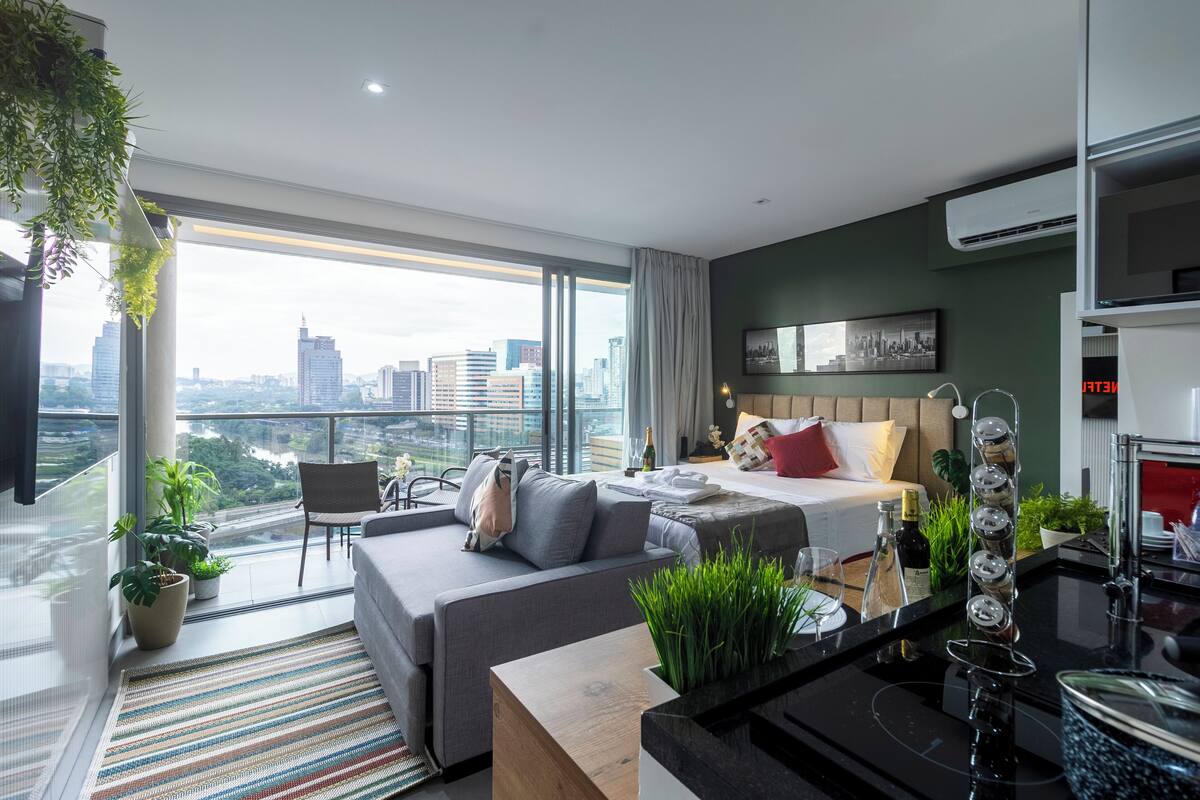 Ein modernes Hotelzimmer mit großem Balkon, einer Couch, einem Bett und einem Essbereich.