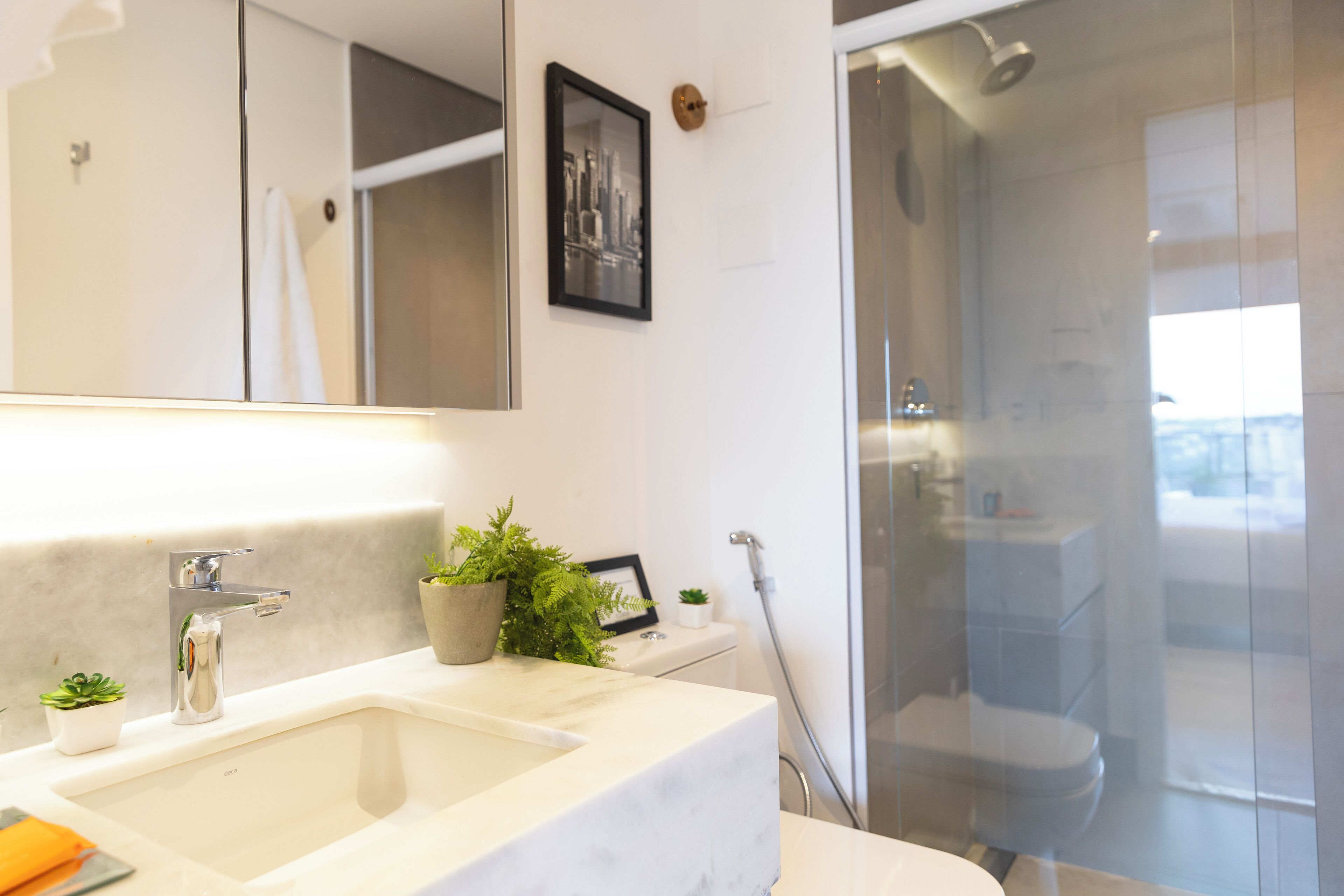 Un bagno moderno con uno specchio grande, un lavandino, una doccia e un water.