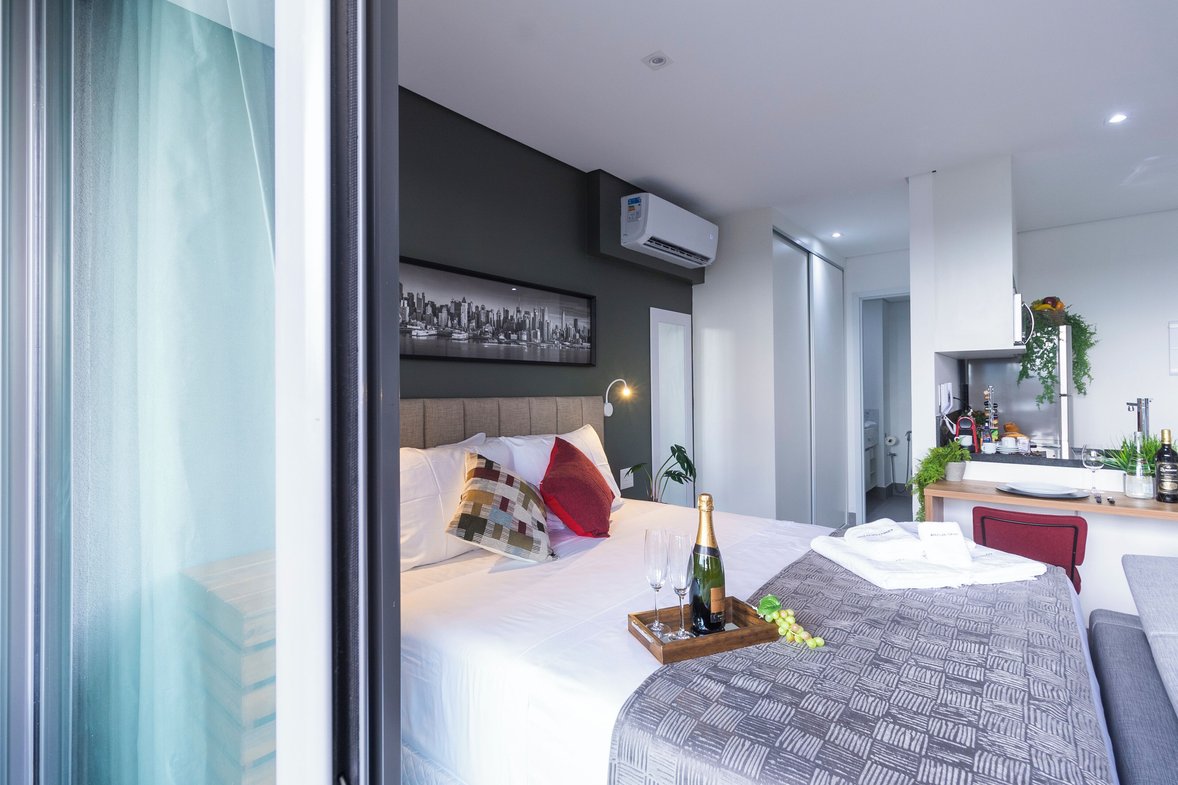 A modern hotel room with a bed, bedside table, and a cityscape artwork on the wall.