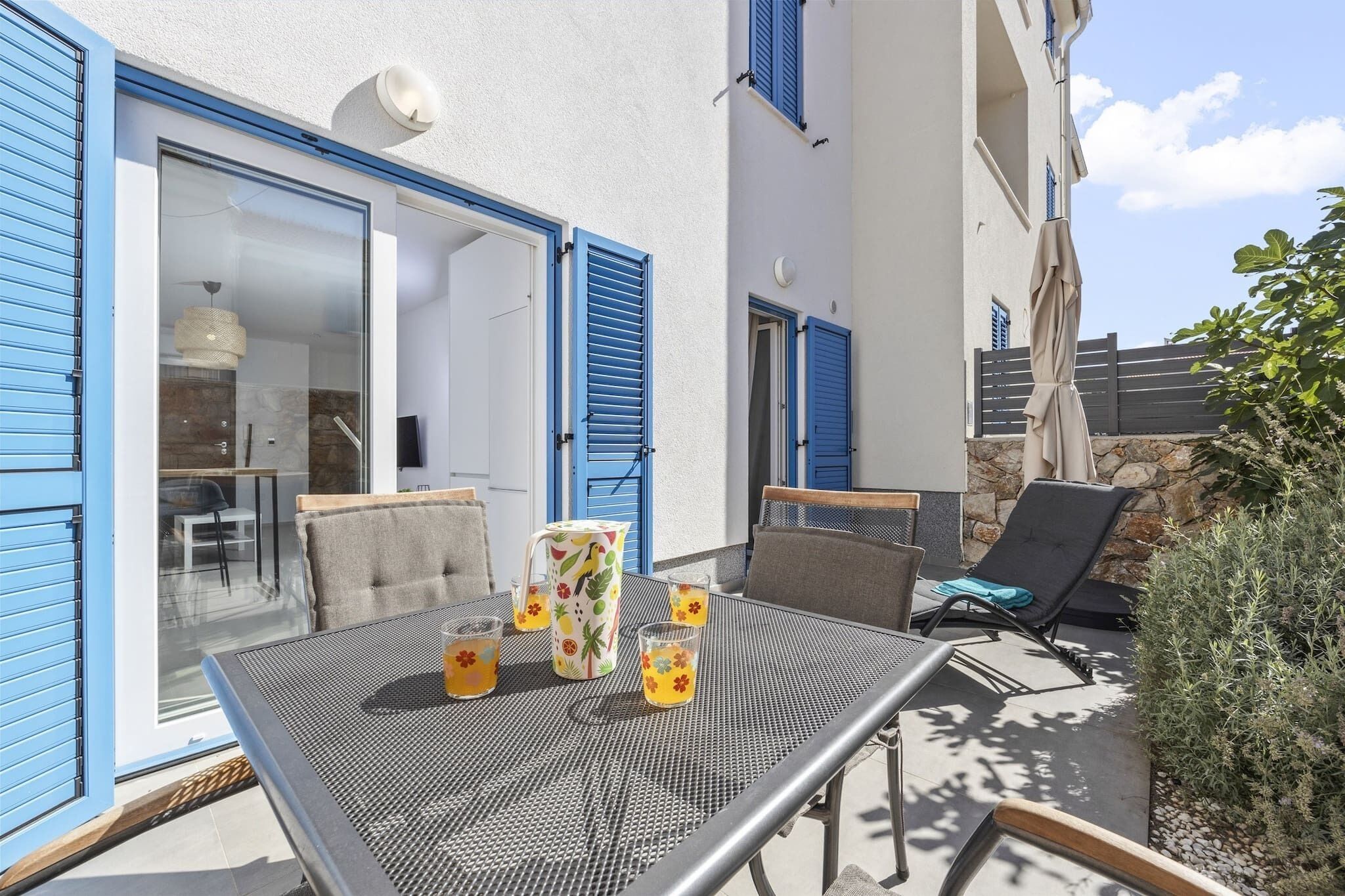 Un patio al aire libre con una mesa lista para dos personas, una silla y un sillón de descanso.