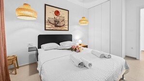 Een moderne hotelkamer met een groot bed, twee hanglampen, een lijstwerk, een nachtkastje en een kledingkast.