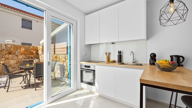Een moderne keuken met witte kasten, een houten aanrechtblad en een inbouwoven.