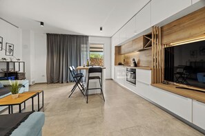 Una cocina moderna con armarios blancos, encimera de madera y horno empotrado.