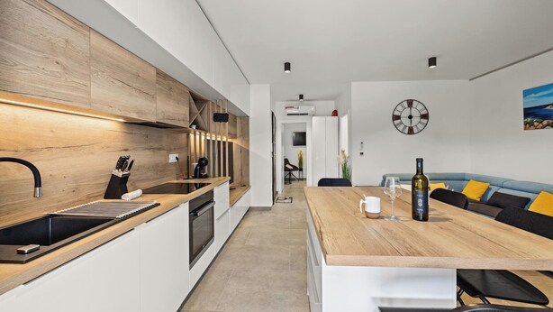 A modern kitchen with a wooden countertop, a sink, and a dining area with a table and chairs. - Couple's Vacation with Jacuzzi - Crepsa Paradise (Cres)