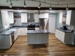 Una cocina moderna con armarios blancos, una isla central, electrodomésticos de acero inoxidable y un salpicadero con diseño.