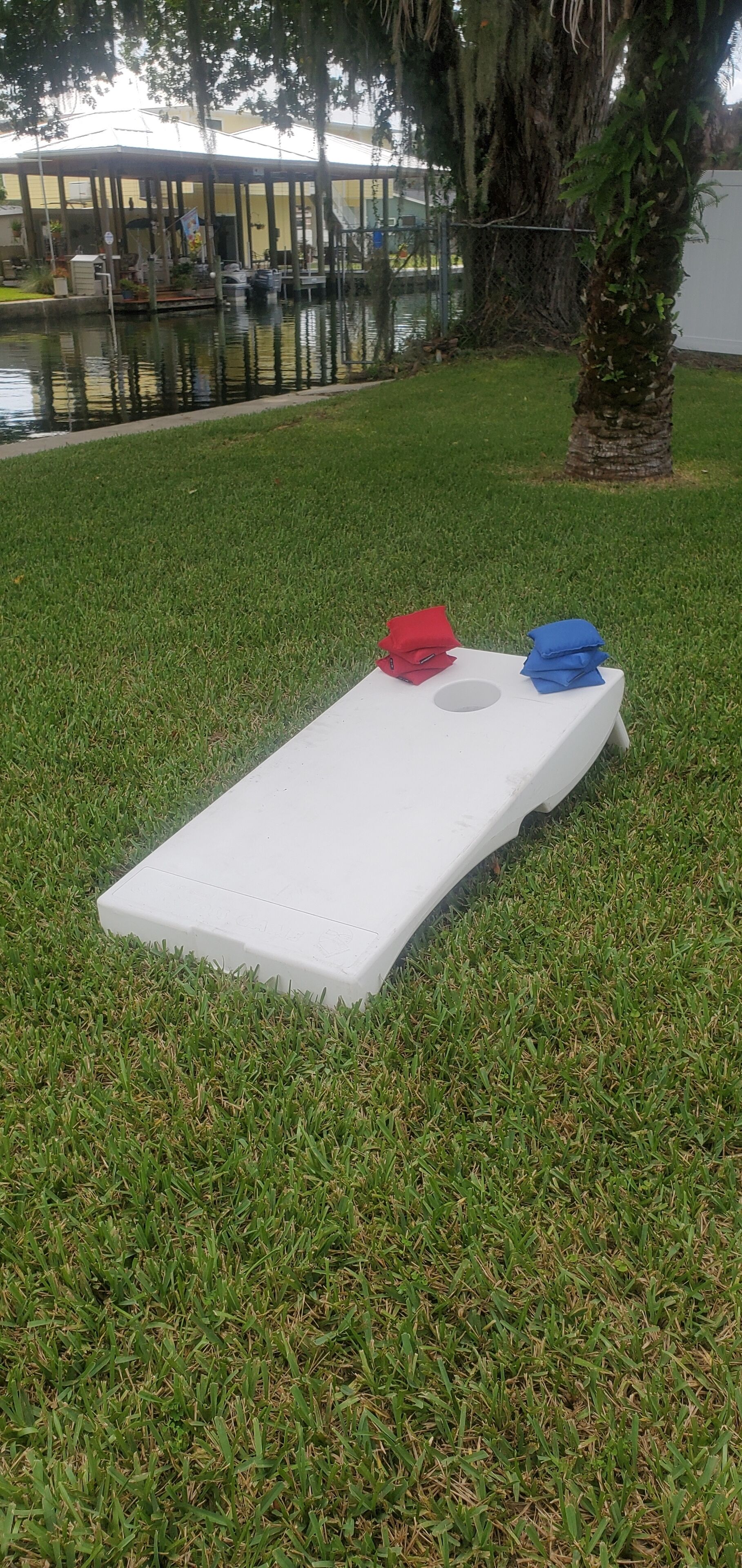 A white rectangular object on a grassy area with a small hole in the center, surrounded by a fence and trees.
