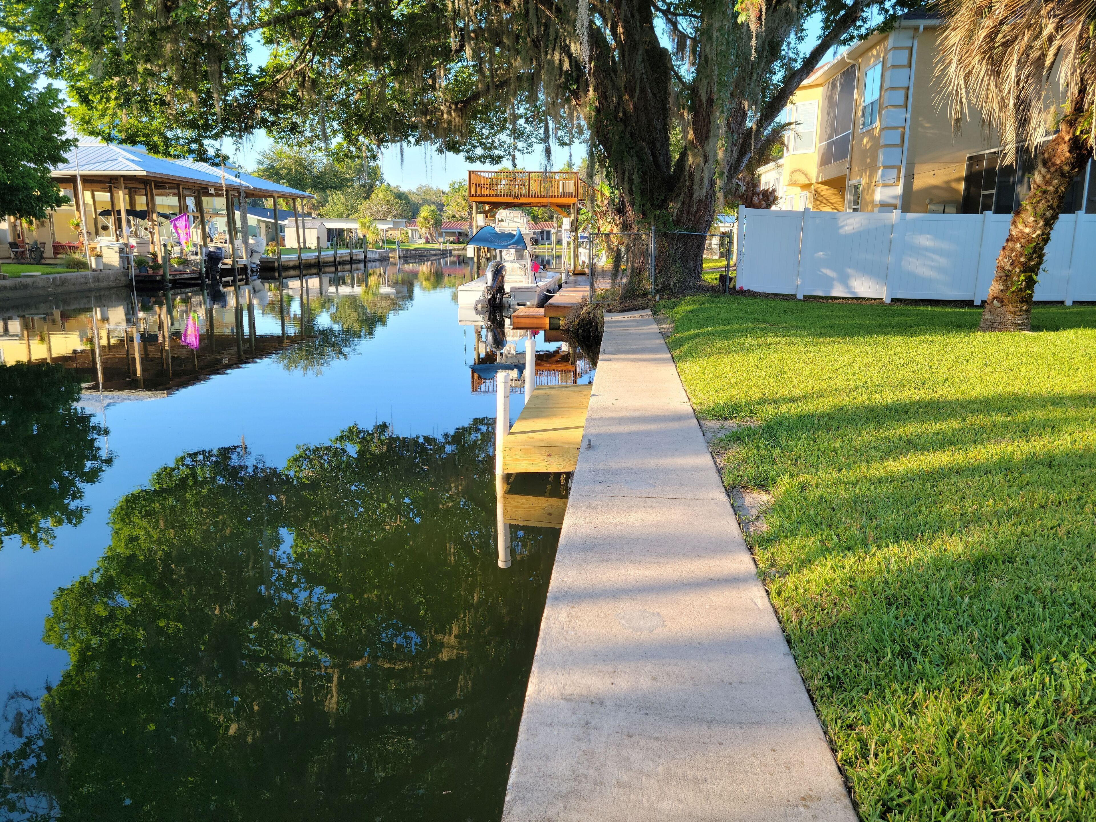 A waterfront property with a dock, a grassy area, and a building with a balcony.