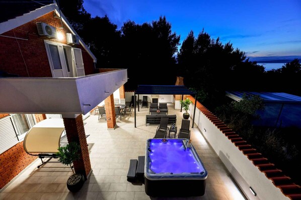An outdoor patio with a hot tub, seating area, and a covered section.