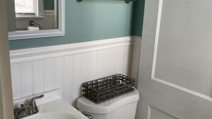 A bathroom with a white sink, a toilet, and a mirror. - Cozy cabin less than 100 steps to the sand! (Hampton)