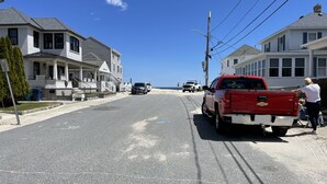 A residential street with houses, a red pickup truck, and a clear blue sky. - Cozy cabin less than 100 steps to the sand! (Hampton)