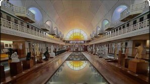 A spacious lobby with a central reflective pool, high ceilings, and a grand staircase leading to upper levels. - Appart Cosy 2P- Proche Métro, Lille à 15 min (Roubaix)