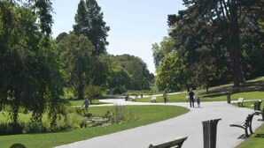 A park with a paved walkway, benches, and trees. - Appart Cosy 2P- Proche Métro, Lille à 15 min (Roubaix)