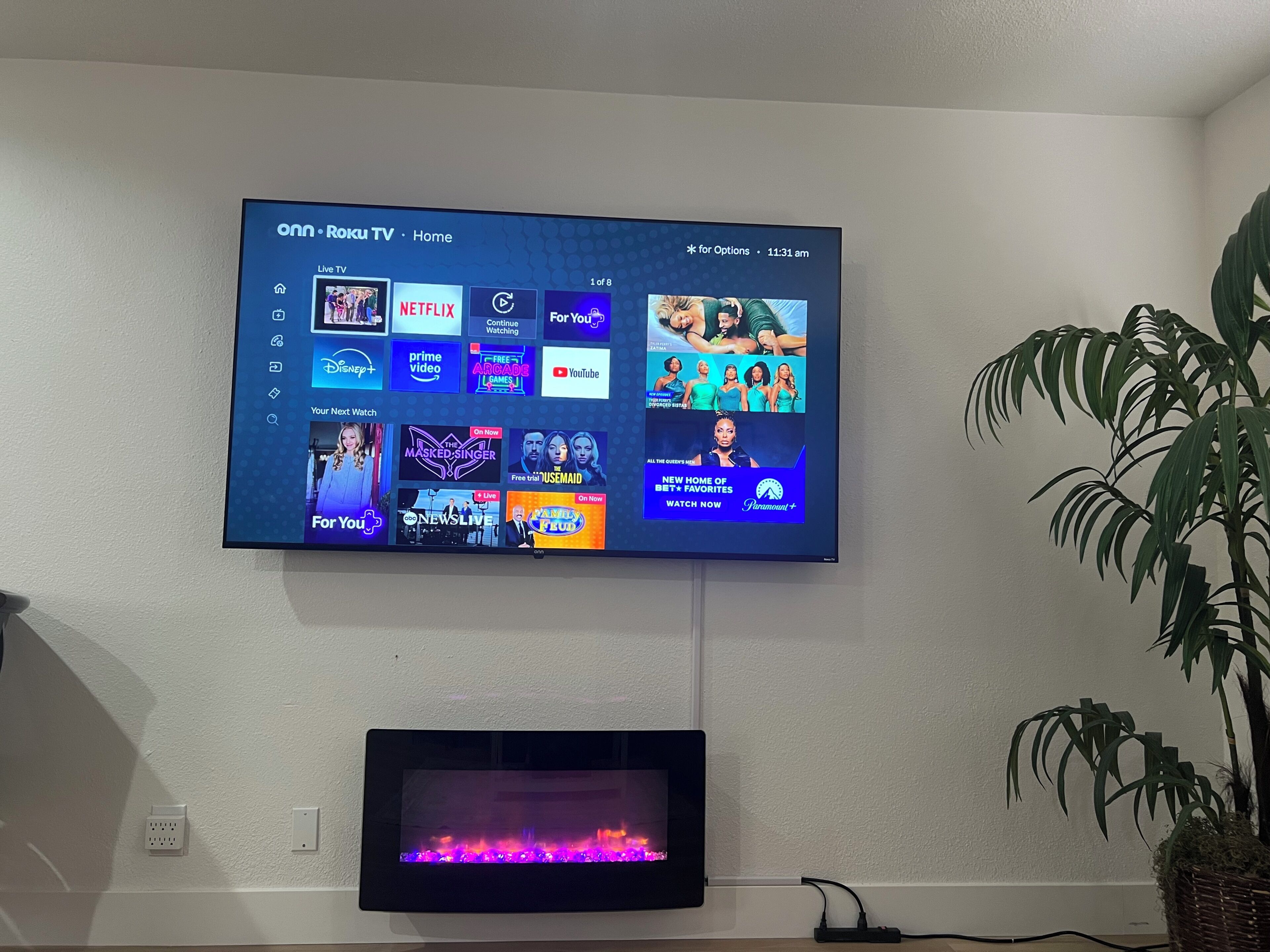 A flat-screen TV mounted on a wall displaying a streaming service interface with various content options.