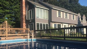 Une maison à deux étages avec une piscine en premier plan.