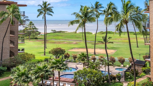 A resort with a pool, outdoor seating, and a view of the ocean. - Aloha Chic Penthouse Vistas (Kihei)