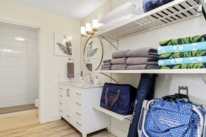 Une salle de bain avec un meuble-lavabo blanc, un évier, un miroir et un porte-serviettes avec des serviettes pliées.