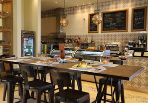 Een restaurant met een lange toonbank, meerdere stoelen en een koffieapparaat.