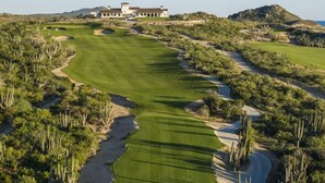 Un parcours de golf avec des bunkers, un club-house et un paysage désertique.