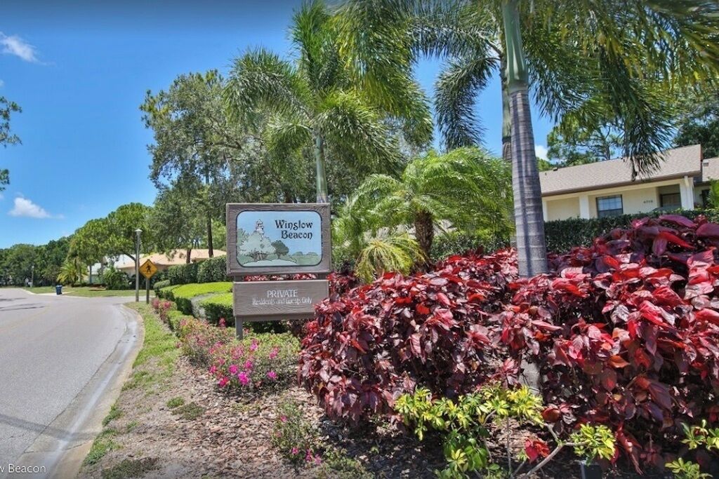 A private property sign with a landscape illustration, surrounded by lush greenery and palm trees.