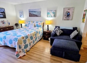 Un dormitorio con cama, sofá, dos mesitas de noche con lámparas y decoración en la pared.
