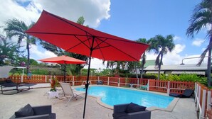 A swimming pool area with lounge chairs and umbrellas. - Bungalow Saphir Idéal Pour Amoureux à 2 Minutes de la Plage, en Bord de Piscine! (Sainte-Rose)